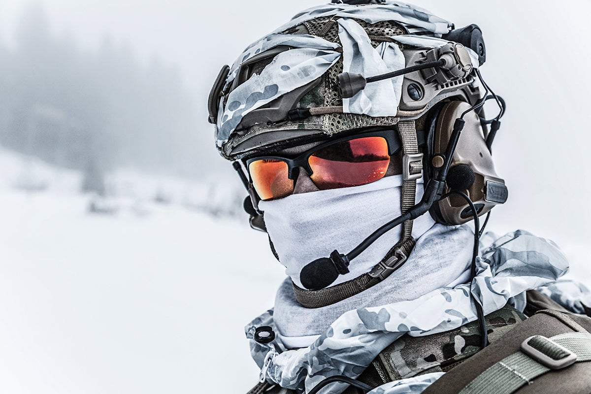 Soldado usando fones de ouvido junto de montanhas geladas