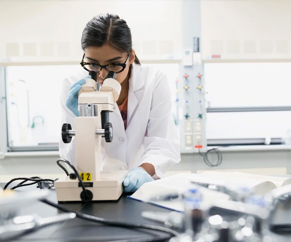 Um cientista olhando através de um microscópio.